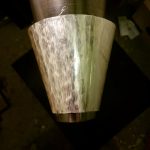 En stomme i form av en kon får sin första planering med blank hammare mot ett konformat järn.