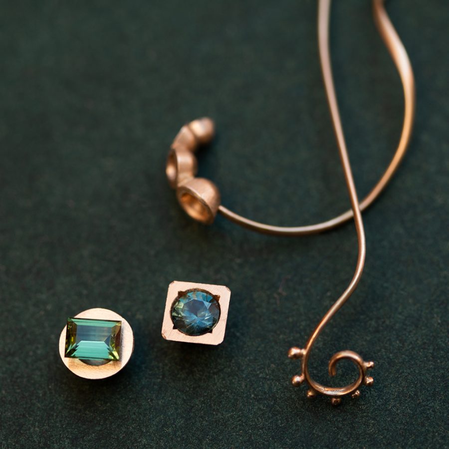 Fattningar av 18k guld, den rektangulära stenen är en turmalin, den runda en tealblå safir. Stenarna är inte satta i materialet, ornament en inte fästa i ett bestämt smycke. Man kommer nån annan stans när man tillåter sig att testa former direkt i materialet. "När jag var barn drömde jag om att bli guldsmed" Turmalin, safir,18k guld. Petronella Eriksson