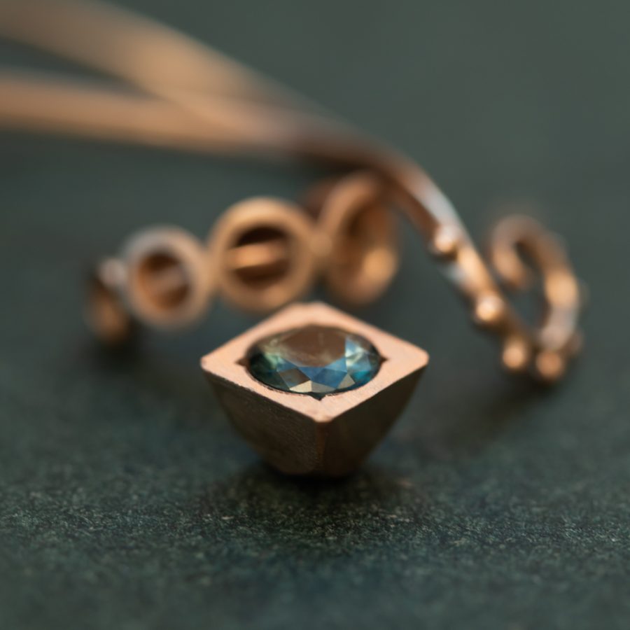 En kvadratisk fattning av 18k guld med en rund tealblå safir. en oval tråd med små små knoppar på. en sträng av fattningar som kanske kan bli en ring? "När jag var barn drömde jag om att bli guldsmed" Turmalin, safir,18k guld. Petronella Eriksson