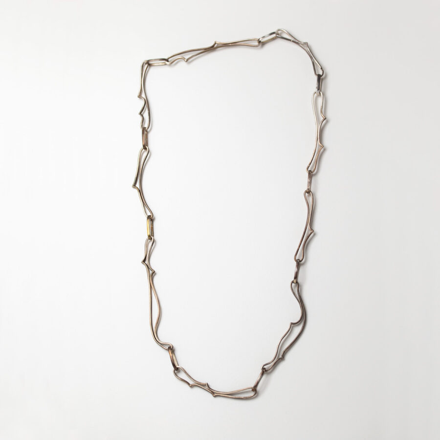 En kedja i patinerat silver med former som jag hämtat ur skisser inspirerade av platforms spelet Silk Song och urmina broderier av rosen stammar med taggar. Att bygga egna silverkedjor Petronella Eriksson